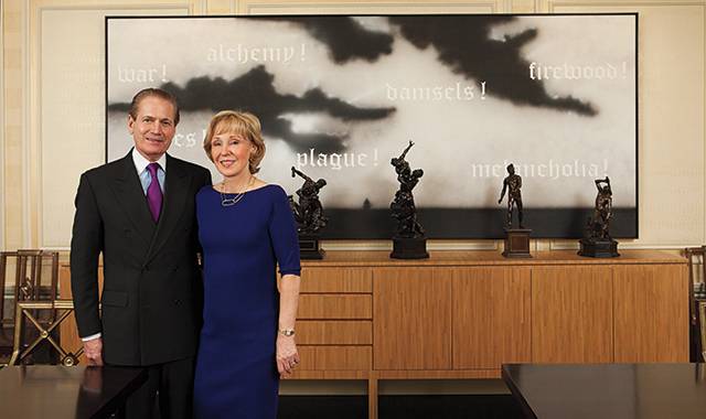 J. Tomilson Hill and his wife, Janine, in their dining room in front of Ed Ruscha’s 17th Century, 1988, and several bronzes cast in the 17th century by Antonio Susini from 16th-century models by the late- Renaissance sculptor Giambologna.
