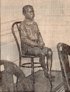 a life-size terra cotta sculpture of a boy seated on an art deco chair.